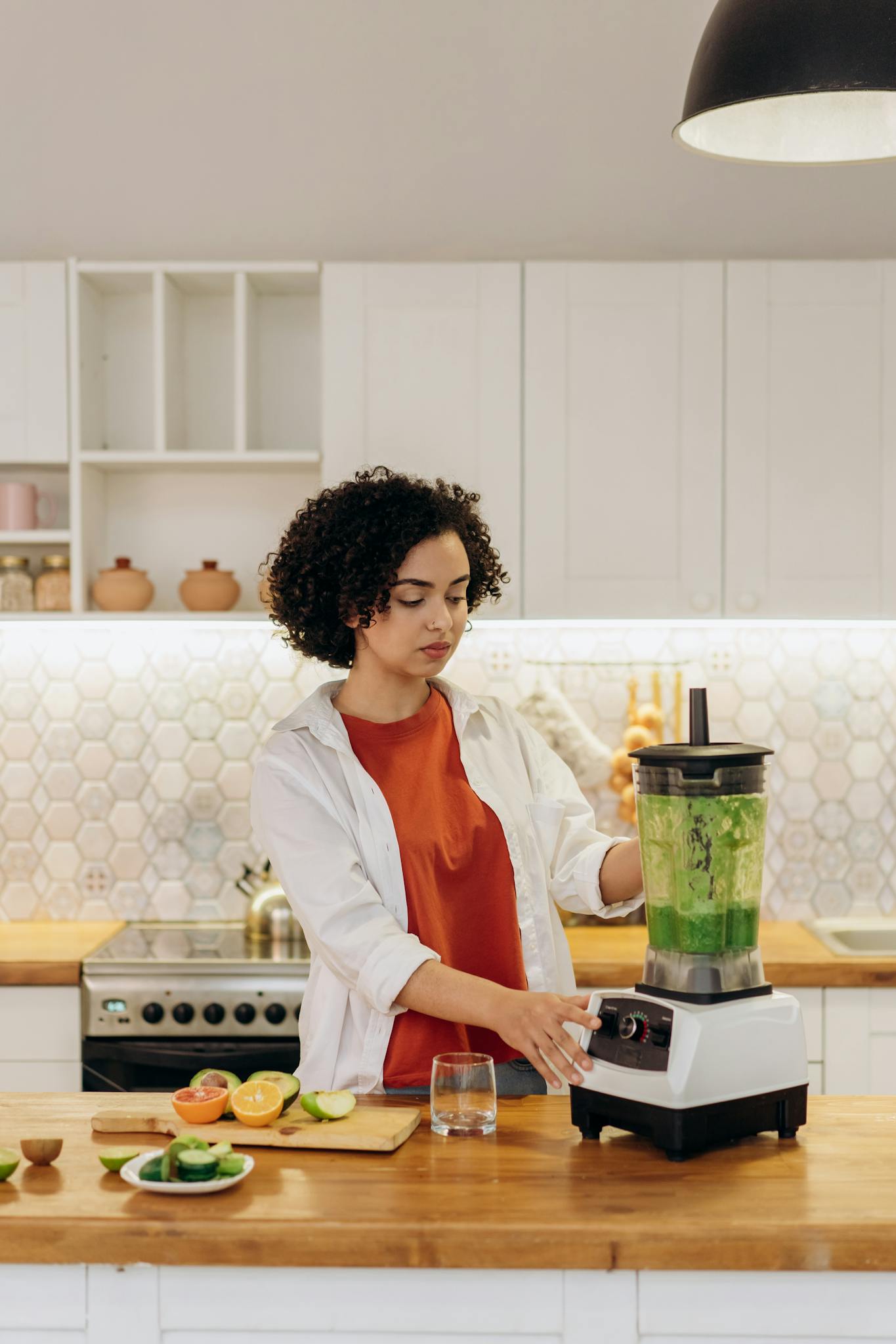A woman blending green smoothie in a stylish home kitchen.